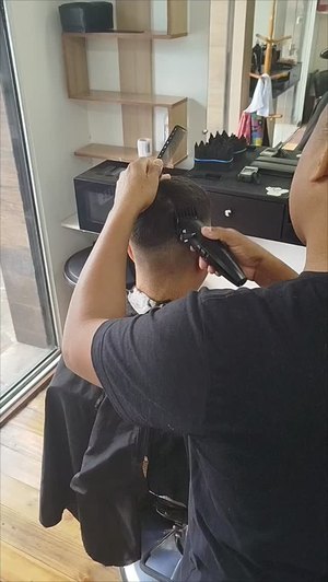 Barbeiro passando a máquina na nuca de um cliente